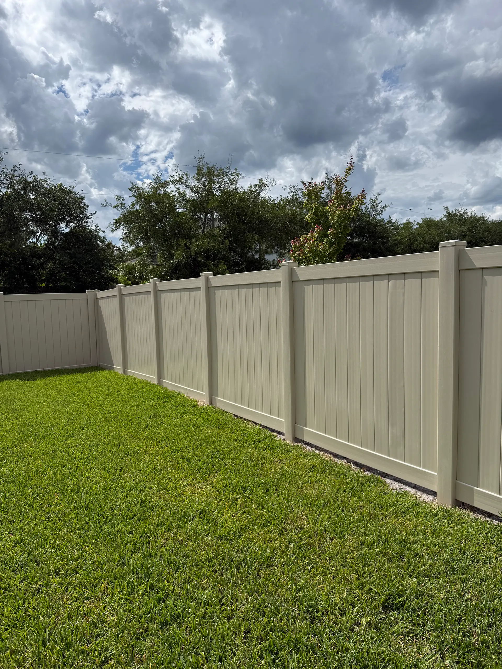 Tan vinyl privacy fence installed across a residential backyard in East Central Florida